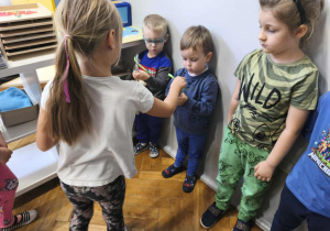 Na zdjęciu widzimy dziewczynki, które wręczją chłopcom drobne upominki.