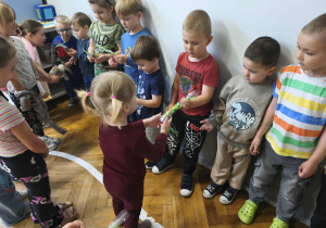 Na zdjęciu widzimy dziewczynki, które wręczją chłopcom drobne upominki.