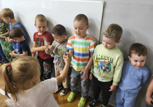 Na zdjęciu widzimy dziewczynki, które wręczją chłopcom drobne upominki.