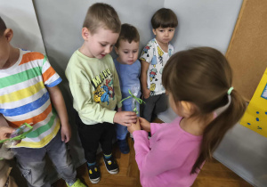 Na zdjęciu widzimy dziewczynki, które wręczją chłopcom drobne upominki.