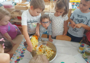 Zdjęcie przedstawia chłopca wsypującego pokrojone warzywa do miski.