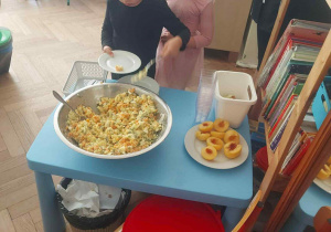 Zdjęcie przedstawia chłopca wkładającego sobie sałatkę na talerz.