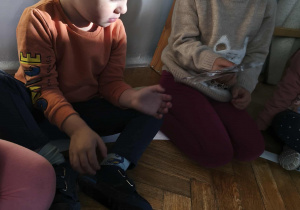 Na zdjęciu widzimy dzieci, które oglądają zdjęcia z poszczególnych etapów życia.