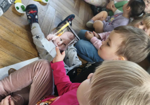 Na zdjęciu widzimy dzieci, które oglądają zdjęcia z różnych etapów życia Solenizantki.