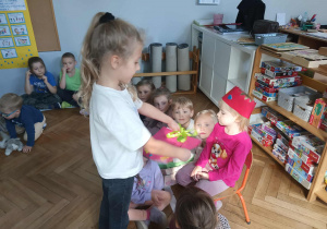 Na zdjęciu widzimy dziewczynkę, która przekazuje Solenizantce książeczkę z rysunkami dzieci.