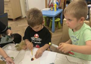 Zdjęcie przedstawia dzieci malujące farbami przy stoliku.