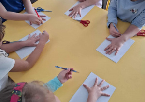 dzieci odrysowują swoje ręce na kartce