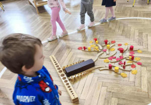 dzieci chodzą po elipsie obserwując wykonane przez nich drzewo z materiału rozwojowego