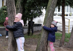 dziewczynki przytulają się do drzewa