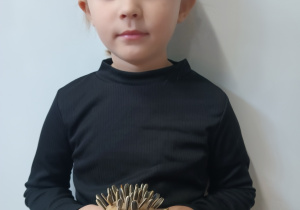 Dziewczynka stoi z jeżem w ręku.