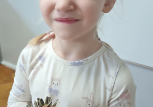 Dziewczynka stoi z jeżem w ręku.