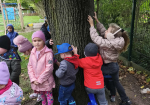Dzieci przytulają się do drzewa.
