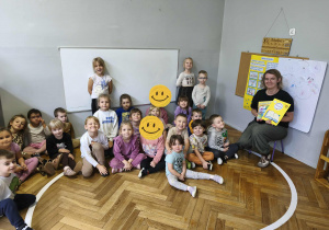 Na zdjęciu widzimy dzieci oraz mamę Poli, która trzyma podziękowanie za zaangażowanie w akcję "Głośnego Czytania" w grupie.