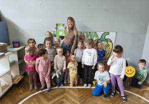 Na zdjęciu widzimy grupkę dzieci oraz mamę Zosi, która trzyma podziękowanie za akcję "Głośnego Czytania" w grupie.