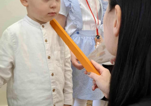 Na zdjęciu widzimy chłopca, który zostaje pasowana na Przedszkolaka naszego Przedszkola.