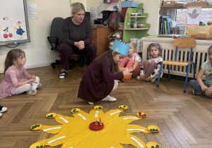 Zdjęcie przedstawia dziewczynkę rozkładającą koraliki na talerzykach.