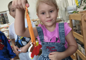 dziewczynka trzyma w ręku zawieszony na swtążce liść z masy solnej