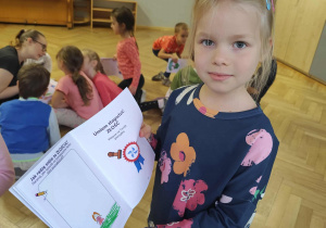 Dziewczynka trzyma swoją książeczkę.
