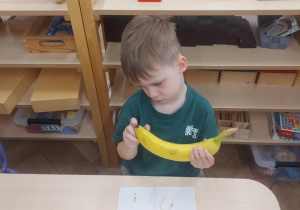 chłopiec, który zastanawia się jak obrać tego banana