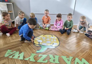 Na zdjęciu widzimy chłopca, który układa część wielkiej papryki.