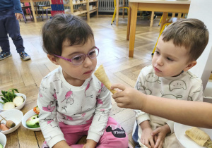 Na zdjęciu widzimy dziewczynkę, która wącha przekrojoną pietruszkę.