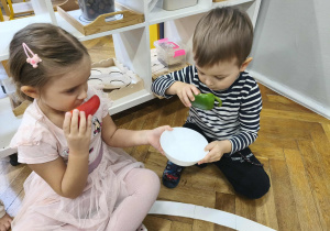 Na zdjęciu widzimy dwójkę dzieci, które wąchają przeprojone papryki - czerwoną i zieloną.