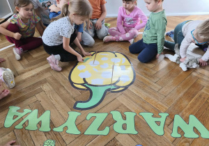 Na zdjęciu widzimy dziewczynkę, która dopasowuje warzywo do jego cienia na wielkiej papryce.