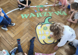 Na zdjęciu widzimy dziewczynkę, która dopasowuje warzywo do jego cienia na wielkiej papryce.