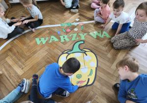 Na zdjęciu widzimy chłopca, który dopasowuje warzywo do jego cienia na wielkiej papryce.