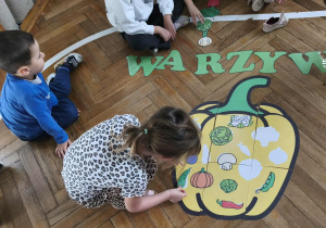 Na zdjęciu widzimy dziewczynkę, która dopasowuje warzywo do jego cienia na wielkiej papryce.