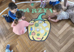 Na zdjęciu widzimy dziewczynkę, która dopasowuje warzywo do jego cienia na wielkiej papryce.