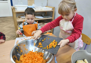 Na zdjęciu widzimy dziewczynkę, która zsuwa marchewkę do miski.