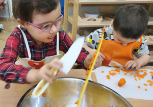 Na zdjęciu widzimy dziewczynkę, która zsuwa marchewkę do miski.