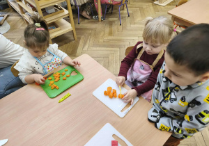 Na zdjęciu widzimy dzieci, które kroją na deskach warzywa do sałatki jarzynowej.