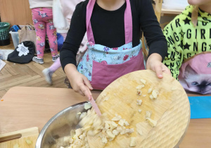 Na zdjęciu widzimy dziewczynkę, która zsuwa pokrojonego selera do miski.