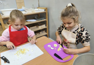 Na zdjęciu widzimy dziewczynki, które kroją jajka na deskach.