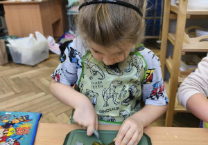 Na zdjęciu widzimy chłopca, który kroi ogórka kiszonego do sałatki.