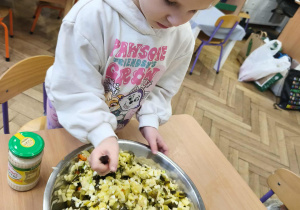 Na zdjęciu widzimy dziewczynkę, która miesza sałatkę w misce.