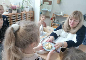 Na zdjęciu widzimy dziewczynkę, która częstuje sałatką Panią z grupy 2.