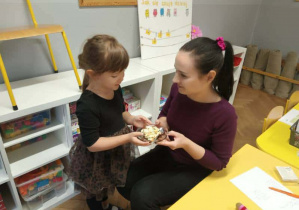 Na zdjęciu widzimy dziewczynkę, która częstuje wykonaną sałatką Panią Dyrektor.
