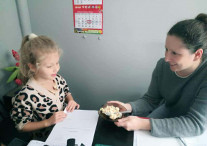 Na zdjęciu widzimy dziewczynkę, która częstuje Panią Ewę wykonaną sałatką.