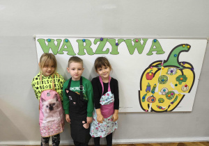 Na zdjęciu widzimy dzieci w kolorowych fartuszkach.