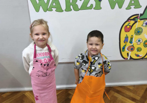Na zdjęciu widzimy dzieci w kolorowych fartuszkach.