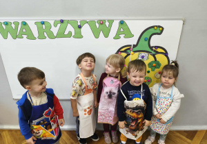 Na zdjęciu widzimy dzieci w kolorowych fartuszkach.