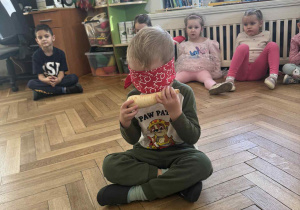 Zdjęcie przedstawia chłopca, który próbuje rozpoznać pietruszkę wąchając ją, mając jednocześnie zasłonięte oczy.