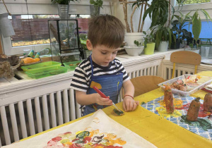 Zdjęcie przedstawia chłopca stemplującego marchewką swoją torbę.