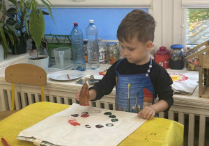 Zdjęcie przedstawia chłopca stemplującego marchewką swoją torbę.