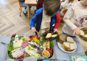 Na zdjęciu widzimy chłopca, który wybiera sobie produkty na śniadanie.