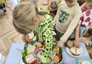 Na zdjęciu widzimy dziewczynkę, która wybiera sobie produkty na śniadanie.