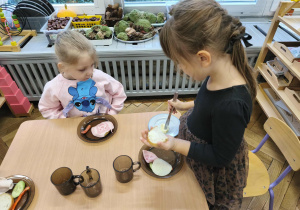 Na zdjęciu widzimy dziewczynkę, która samodzilnie smaruje sobie chleb masłem.